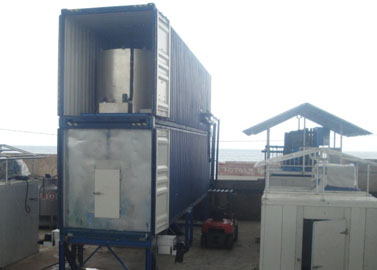 Containerized flake ice machine with rake ice storage room